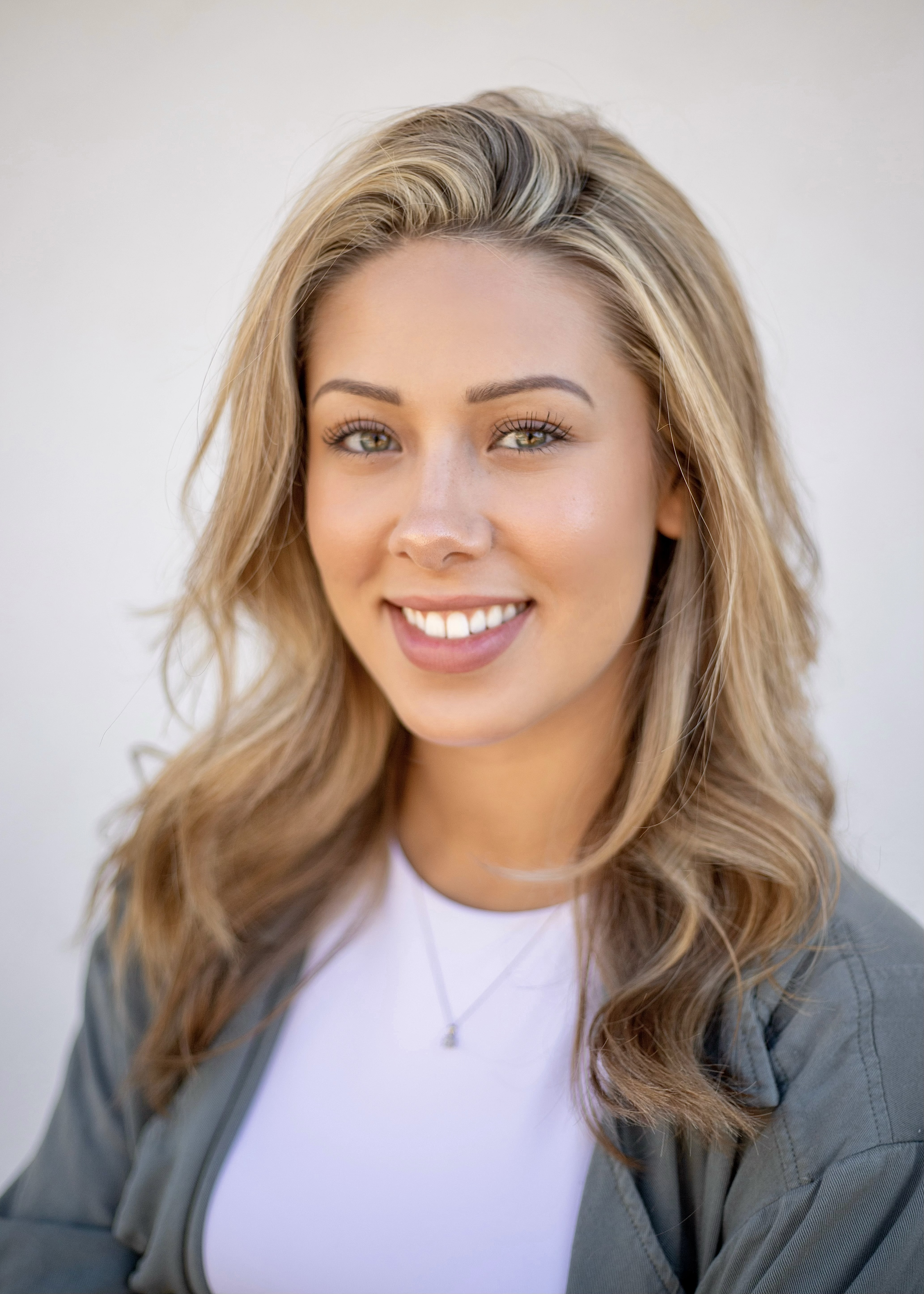 A professional and approachable portrait of a female financial coach with a warm smile, sitting in a bright, modern, minimalist home office.